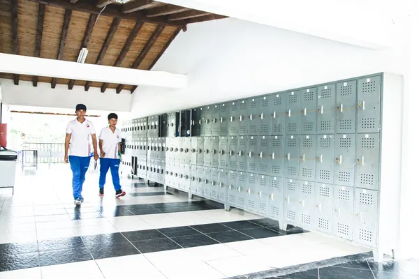 Estudiantes con el uniforme del colegio caminando por el pasillo de los lockers